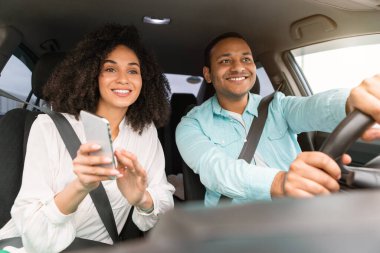 Araba Gezisi Planlama. Neşeli Orta Doğulu eşler araba kullanıyor, telefon kullanıyor, güzergahı tarıyor ve otomobilde oturarak seyahat ediyor. Aile Çifti Seyahat Macerası ve Teknolojisinden Hoşlanıyor