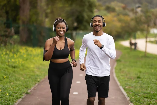 Pozitivní Mladý Černý Pár Bezdrátových Sluchátkách Poslouchat Hudbu Běh Letním — Stock fotografie