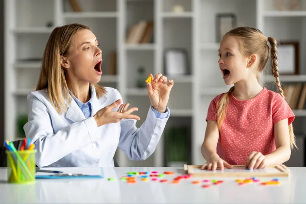 Effective Speech Therapy. Therapist Lady Having Lesson With Cute Little Girl, Professional Logopedist Teaching Articulation Of Letter A To Female Child, Improve Kids Language Via Interactive Games