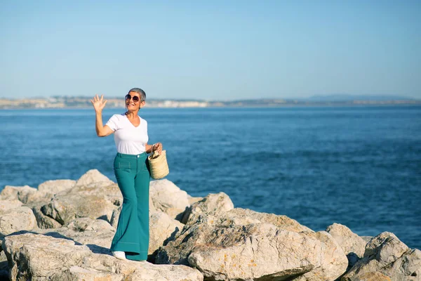 夏曼快乐的欧洲成熟女士挥手拍照站在近岸的户外 女人在海滨享受假期和阳光灿烂的日子 梦想假期的概念 — 图库照片
