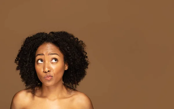 护肤常规概念的利弊 茫然失措的年轻的半裸黑人女子看着广告的复制空间 被隔离在棕色的工作室背景下 — 图库照片
