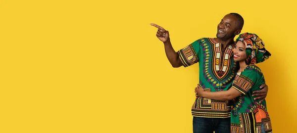 コピースペースと笑顔を指して カップルは 国家のアフリカの衣装を着て 素敵な広告を見て パノラマ — ストック写真