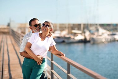 Mutlulukla sabitlenmiş. Mutlu Olgun Eşler Açık Deniz Yatları 'nda birbirlerine sarılıp yaz kıyafetleri ve güneş gözlüğü takıyorlar. Sevgili Çift Emekliliğin ve Yaz Gezisinin tadını Çıkartıyor