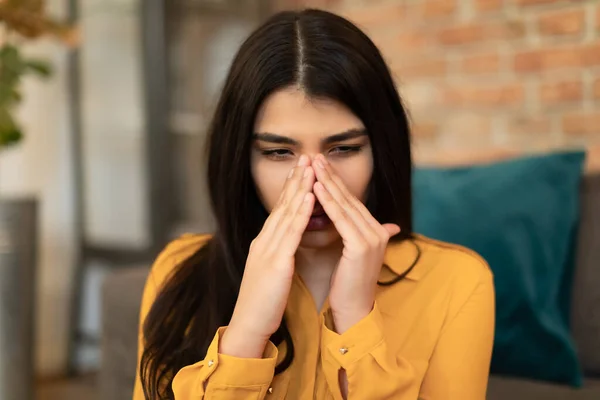 鼻の橋に触れる若いスペイン人女性 鼻炎に苦しんで 季節性アレルギーや関節炎 体調が悪いです 自宅でソファに座って クローズアップポートレートショット — ストック写真