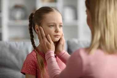 Çocukluk sorunları kavramı. Genç bir anne, evde tartıştıktan sonra gücenen üzgün kızını teselli ediyor. Çocuğunu önemseyen bir anne, oturma odasında birbirine bağlanıyor.