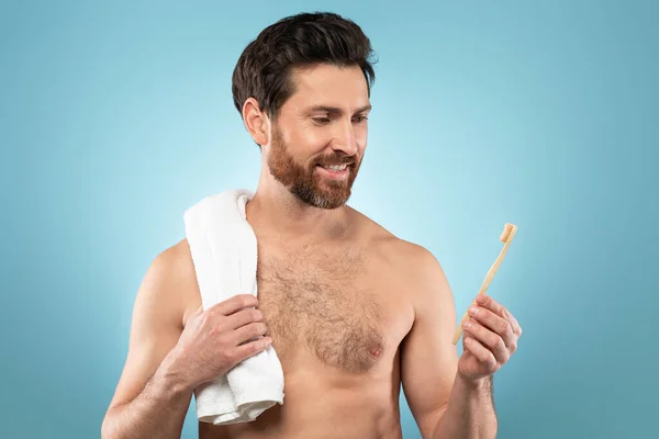 ハンサムな中年の男性は 青の背景にポーズを口腔衛生を楽しんで 歯ブラシを保持肩にタオルで おはよう 美容ケア 毎日の手順 ケアコントロール — ストック写真