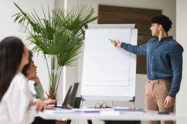 Profesyonel Sunum. Arap iş adamı, şirket toplantısında konuşma yapıyor,... beyaz tahtaya işaret ediyor,... modern ofiste başlangıç stratejisini ve fikirlerini anlatıyor. Seçici Odaklanma