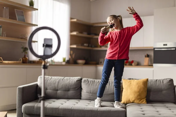 stock image Funny Little Girl Shooting Video For Social Media, Singing And Dancing At Home, Cheerful Preteen Female Child Holding Microphone, Capturing Content With Smartphone And Selfie Circle