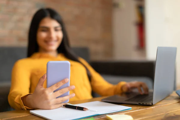 教育用ガジェット 携帯電話を使用して幸せな学生の女性は 机の上にノートパソコンで座って 10代の女性のテキストメッセージやオンライン保持スマートフォンを学ぶ Learning — ストック写真