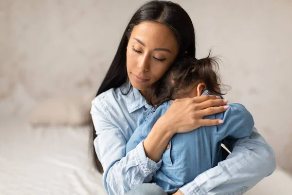 stock image Baby Care. Japanese Mother Holding Child Daughter In A Loving Warm Hug, Snuggling And Hushing Little Toddler Girl In Cozy Bedroom Indoors. Mommy Caring For Infant At Home. Babysitting Concept