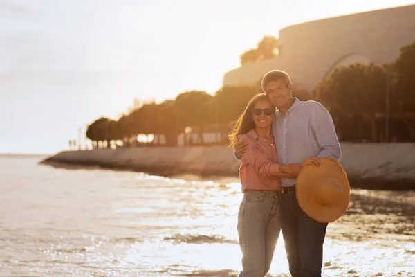 日没時にビーチで抱擁幸せな中年夫婦 ロマンチックな熟女と女性は屋外で一緒にポーズ 海の近くに立って愛する配偶者 カメラで抱擁と笑顔 スペースをコピー — ストック写真