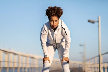 Dışarıda koştuktan sonra dinlenen yorgun siyah kadın portresi, Kardiyo antrenmanından sonra nefes alan yorgun Afrikalı Amerikalı kadın, Sabah Koşusundan sonra dinlenen atletik kadın.
