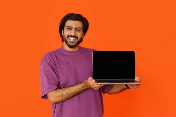 Pozytywny Przystojny Młody Indianin Pokazujący Nowoczesny Laptop Czarnym Pustym Ekranem — Zdjęcie stockowe