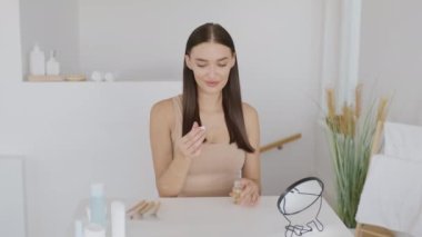 Ayrılık tedaviyi bitirir. Zarar görmüş saçlara serum uygulayan kaygısız genç bayan saç bakım için kozmetik kullanıyor yatak odasındaki aynaya bakıyor yavaş çekim, boş alan.