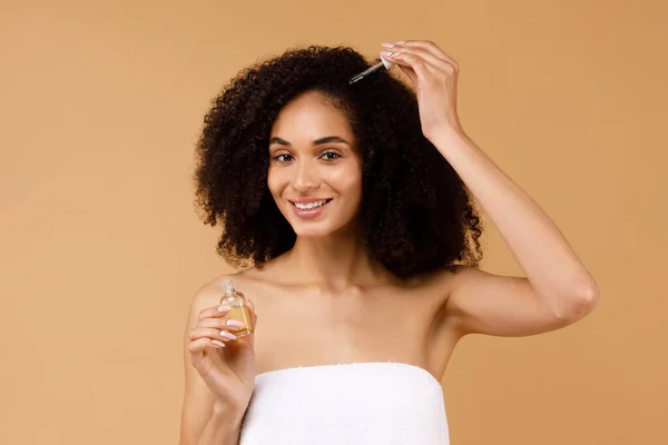 Wanita Hitam Cantik Yang Mengaplikasikan Serum Untuk Perbaikan Rambut Memakai — Stok Foto
