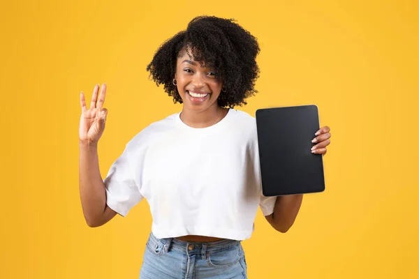 肯定的な千年アフリカ系アメリカ人の巻き女性は 空白の画面でタブレットを表示し 黄色の背景に隔離された をジェスチャーにします 推薦と承認 広告とオファー ソーシャルメディアアプリとブログ — ストック写真