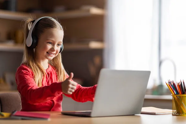 Virtual Classroom. Happy Little Schoolgirl Looking At Computer Screen And Showing Thumb Up, Smiling Preteen Female Child Wearing Headphones Celebrating Achievements In Online Lesson, Copy Space