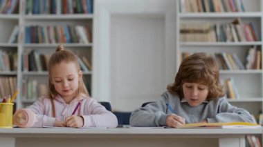 Çalışma süreci. Sevimli ergen erkek ve kız öğrenciler sınıfta birlikte oturup öğretmenlerini dinliyorlar, tahtaya bakıyorlar ve notlar yazıyorlar, boş yer var.