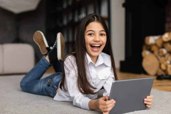 Gadget Fun 快乐的阿拉伯小女孩使用数码平板电脑 玩网络游戏 享受网上娱乐放松躺在沙发上在家里 微笑着拍照 周末及康体 — 图库照片