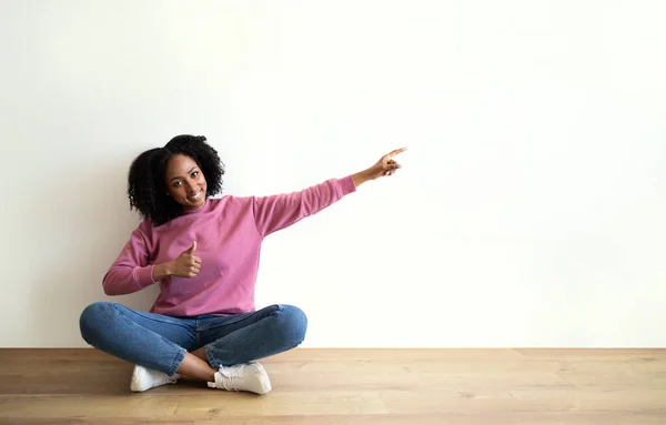 Glad Millennial African Curly Lady Casual Sits Floor Points Finger — стоковое фото