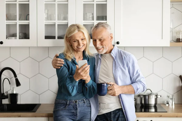 Glada Äldre Par Som Använder Smartphone Tillsammans Medan Avkopplande Köket — Stockfoto