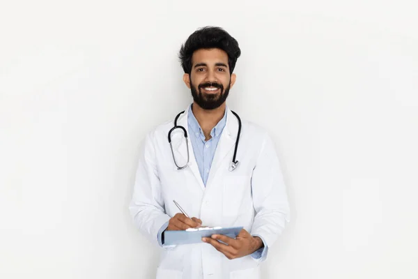 Barátságos Mosolygós Jóképű Fiatal Szakállas Indiai Orvos Orvosi Köpenyben Sztetoszkóppal — Stock Fotó