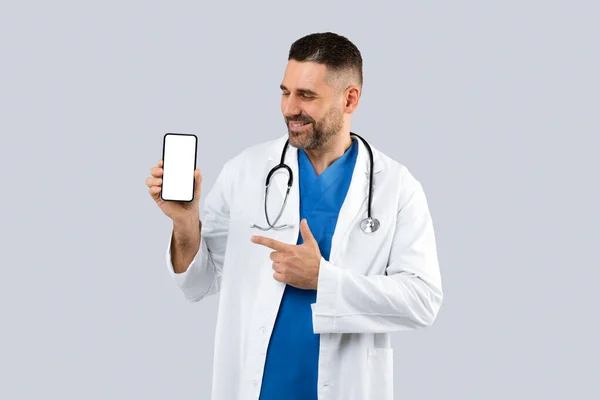 Przystojny Terapeuta Pokazujący Telefon Komórkowy Pustym Ekranem Reklamującym Aplikację Medyczną — Zdjęcie stockowe