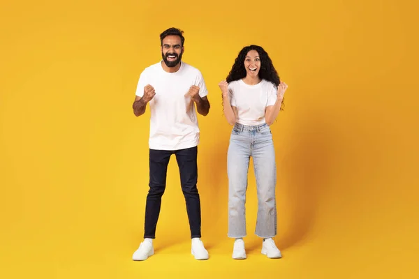 快乐的阿拉伯语配偶高喊颤抖的拳头对着相机微笑 庆祝站在黄色工作室背景上的成功 感情用事的年轻夫妇 — 图库照片