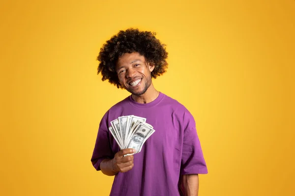 티셔츠를 곱슬머리의 남자는 오렌지 스튜디오에 고립된 지폐를 보유하고 경제적 광고와 — 스톡 사진