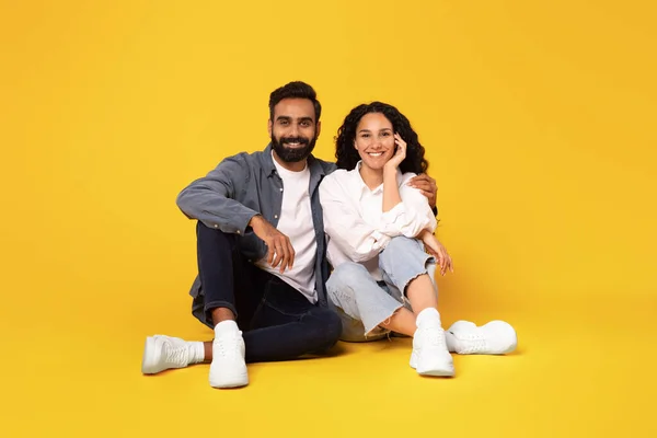 ロマンチックな愛 黄色のスタジオの背景の上にカメラに笑顔を座っと抱擁幸せなアラビア語の夫婦 肯定的な感情を受け入れる愛の配偶者の完全な長さショット — ストック写真