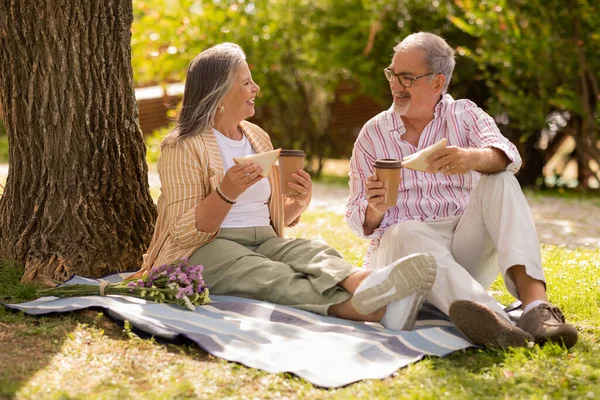 快乐的欧洲裔夫妇与一杯咖啡外卖 三明治坐在格子 享受约会 野餐公园在夏天的周末 业余时间 午餐和食物 — 图库照片