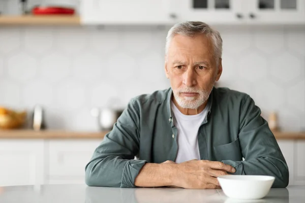 老年人的抑郁症 心烦意乱的老年人坐在厨房的餐桌前 沉思压抑的绅士在家里的画像 灰白头发的男人的忧郁与孤独 复制的空间 — 图库照片