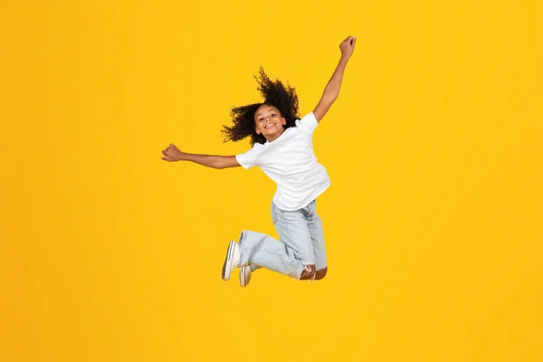 유쾌하게 곱슬곱슬 티셔츠를 여학생은 재미있고 점프하고 허공에서 얼어붙는 자유를 즐기며 — 스톡 사진