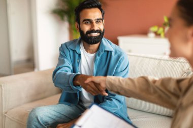 Profesyonel yardım. Ofiste psikoterapist ile tokalaşan neşeli bir Arap adam. Müşteri, danışma sırasında uzman danışmanla el sıkışırken. Seçici Odaklanma