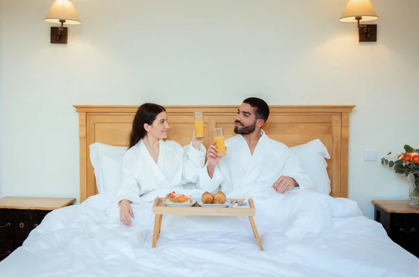 Cheerful Couple Enjoying Breakfast Clinking Glasses Orange Juice Relaxing Bed — Stock Photo, Image