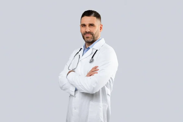 医療サービスの概念 中年男性医師セラピストの肖像で制服姿で折り畳まれた腕と見ますカメラ上のライトスタジオの背景 コピースペース — ストック写真