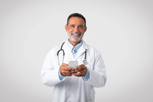 Terapeuta Médico Maduro Caucasiano Alegre Casaco Branco Digitando Smartphone Isolado — Fotografia de Stock