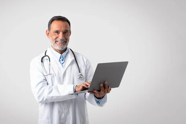 Cheerful Caucasian Mature Man Doctor White Coat Typing Laptop Isolated — Stock Photo, Image
