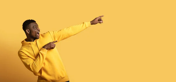 身穿黄色连帽衫 情绪激动的年轻非洲裔美国人 空空荡荡地登广告 黑人男子指指点着黄色工作室背景 网页横幅 — 图库照片