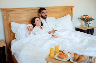 Balayı Sabahları. Birbirine aşık çift, rahat bir yatakta, sabahları otelin iç kısmında kahvaltı tepsisiyle sarılıyorlar. Eşler tatil sabahı dinleniyor. Lüks ve Rahatlama
