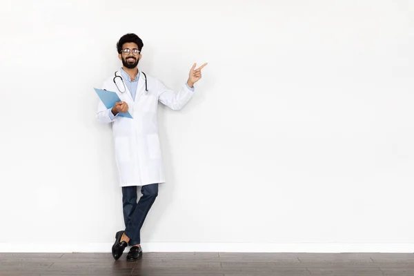 웃음을 중년의 의사가 청진기와 차트를 배경에 복사된 공간을 배너를 착용하고 — 스톡 사진