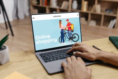 Siyah adam online alışveriş için dizüstü bilgisayar kullanıyor, moda mağazasından kıyafet alıyor, evden alışveriş yapıyor. Sipariş teslimatı, alış veriş, uygulama ve yeni kıyafetler için web sitesi