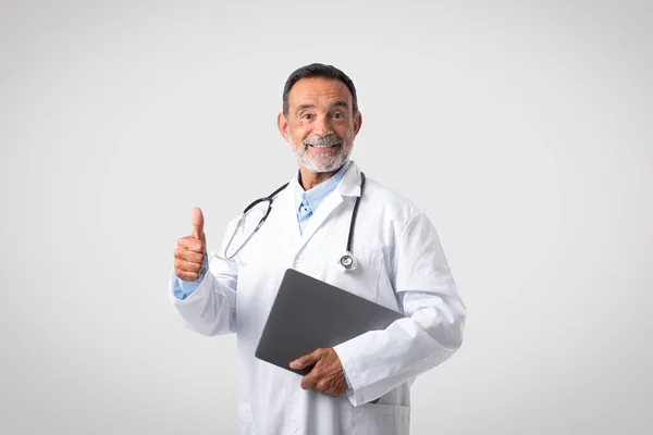 Beyaz Önlüklü Neşeli Beyaz Tenli Olgun Doktor Parmak Yukarıda Gri — Stok fotoğraf