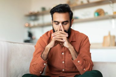 Sorunları düşünüyorum. Bunalımlı Hintli adam migreni hakkında kafa yoruyor, evde konsantre olmak için gözleri kapalı, burnuna dokunarak poz veriyor. Depresyon ve Zor Beyin Çalışması