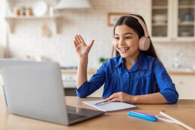Çevrimiçi Öğrenme Mükemmelliği. Video Çağrı Dersinde Kulaklıklı Liseli Kız, Evdeki Masa Başında Oturan Laptop ile Uzaktan Öğreniyor. E-Öğrenme Başarı Konsepti