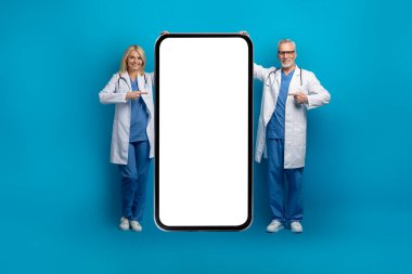 Teletıp, sanal danışmanlık, e-sağlık. Kafkasyalı, beyaz ekranlı, mavi arka planda izole edilmiş, tıpta kıdemli doktorlar büyük bir telefonu işaret ediyor.