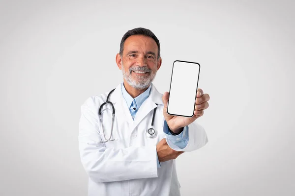 Χαρούμενος Καυκάσιος Ώριμος Άντρας Γιατρός Λευκό Παλτό Δείχνει Smartphone Λευκή — Φωτογραφία Αρχείου