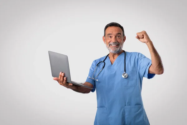 Szczęśliwy Podekscytowany Biały Starszy Lekarz Niebieskim Mundurze Laptopem Wykonującym Gest — Zdjęcie stockowe