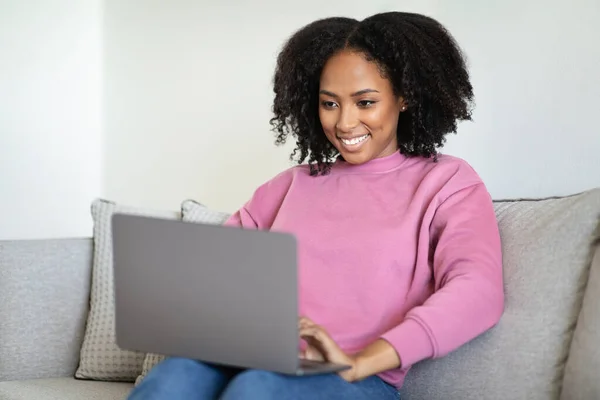 Mulher Negra Millennial Alegre Digitando Laptop Mensagem Sentado Sofá Interior — Fotografia de Stock