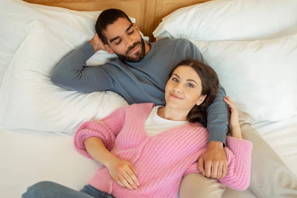 Young Mixed Couple Hugging Lying Bed Embracing Smiling Camera Cozy — 스톡 사진